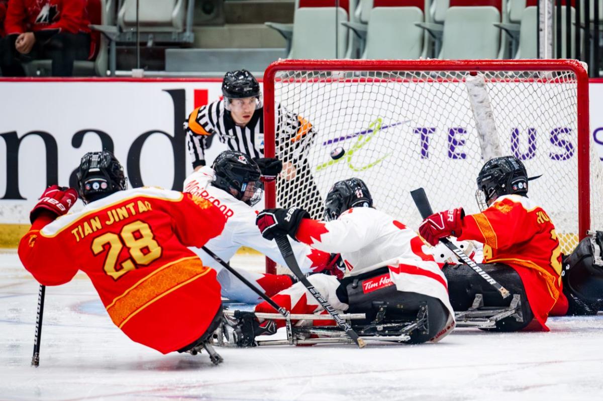 A Para ice hockey official watching four players